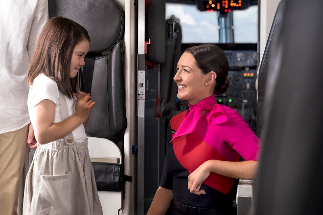 Female cabin crew welcoming young girl onboard