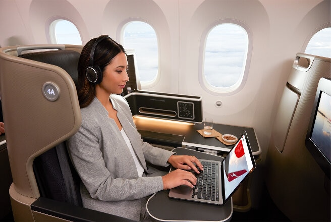 Female business customer sitting at window seat on B787 flight. Wifi login on laptop screen.