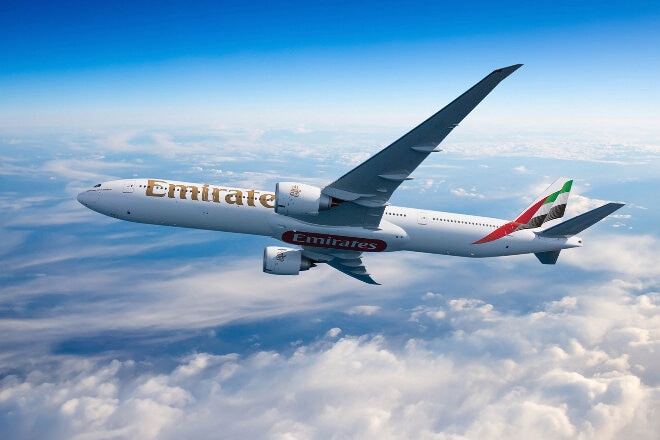 Emirates aircraft banking in flight above the clouds