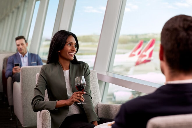 lady sitting in Qantas Club holding a glass of wine