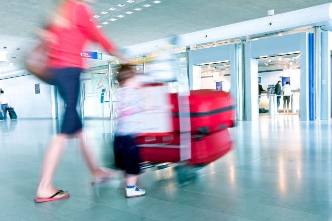 Lady walking through airport with child and luggage