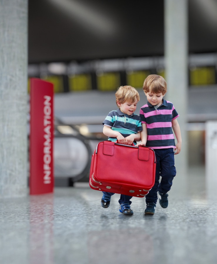 Children carrying small suitcase at airport