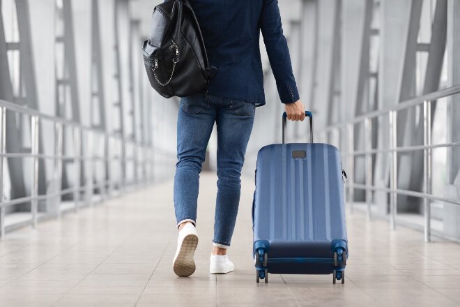 Lady walking through the airport with a blue suitcase