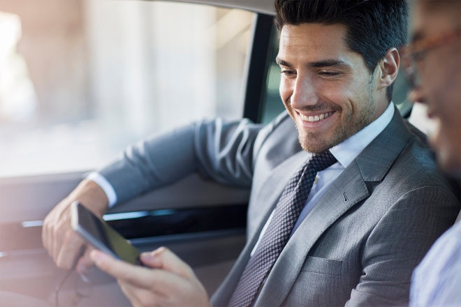 Man in suit in car looking at phone