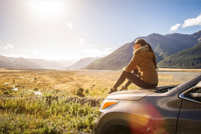 Women sitting on car looking at mountain