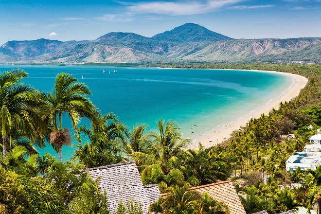 Tropical beach, sand and palm trees with mountains in far view