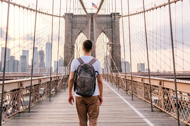 Male walking across Brooklyn Bridge