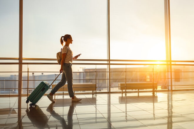 Lady walking through the airport with a blue suitcase