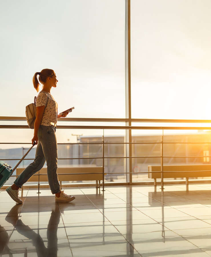 Women walking through terminal with small sized wheelie case carry-on baggage