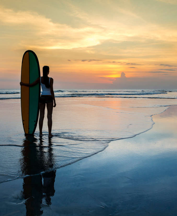 Surfer on beach at sunset