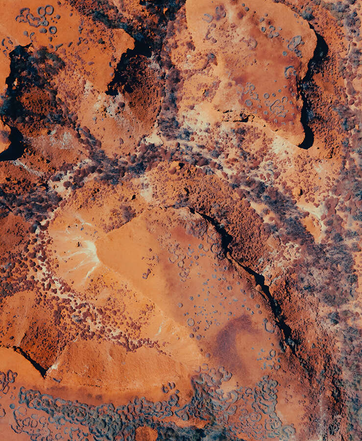 Abstract Aerial View of Desert Terrain With Red Rocks and Dirt