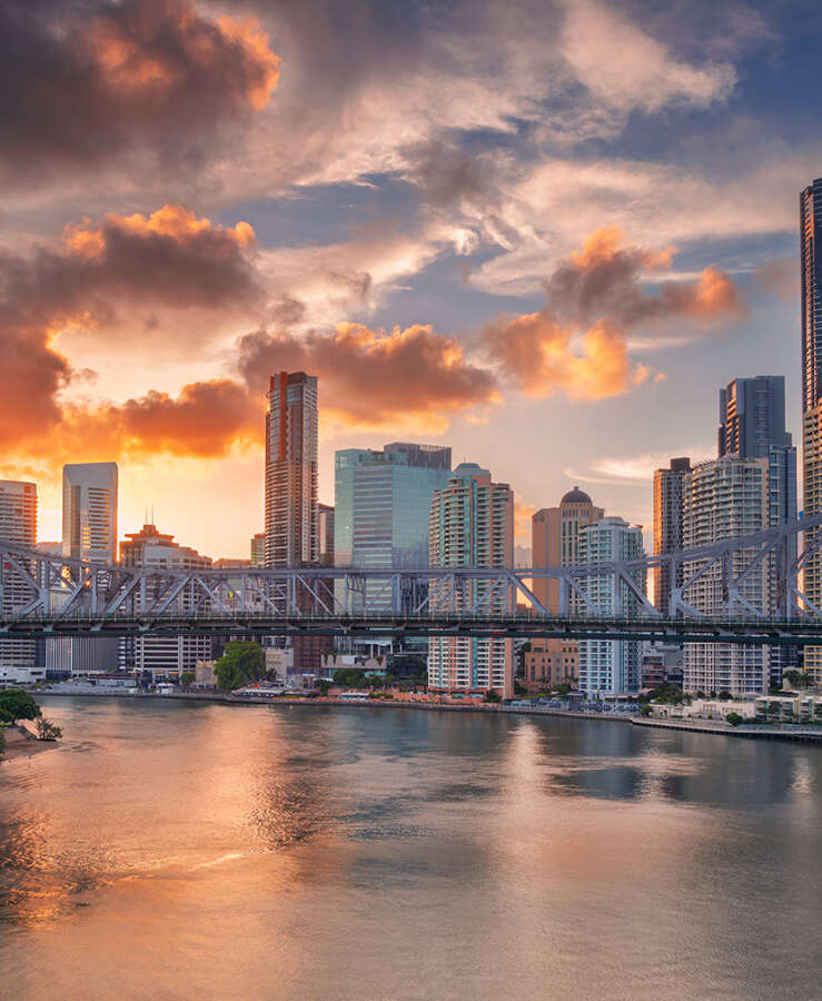 Cityscape of Brisbane skyline with the Story Bridge and reflection of the city in Brisbane River at sunset.