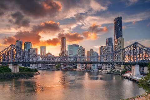 Cityscape of Brisbane skyline with the Story Bridge and reflection of the city in Brisbane River at sunset.