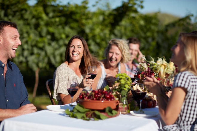 Table of guests dining outside with wine