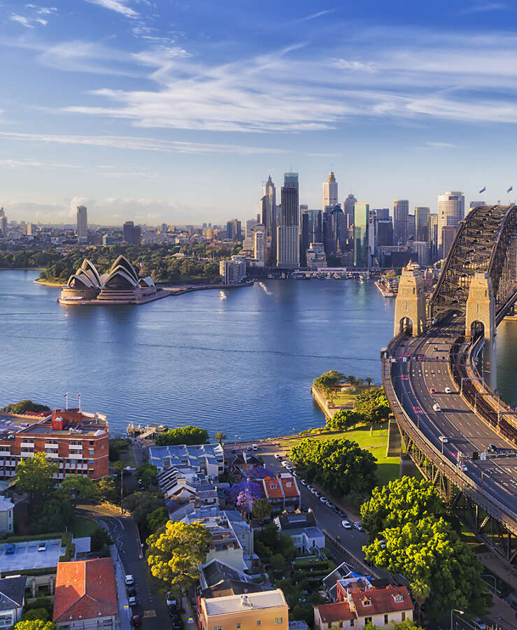 Cahill express way to the Sydney Harbour bridge across Sydney harbour towards city CBD landmarks in aerial eleveated wide view under blue morning sky.