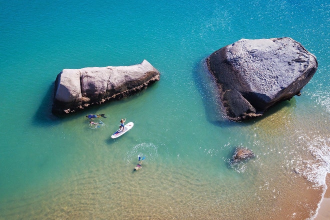 paddleboarders on water near rocks