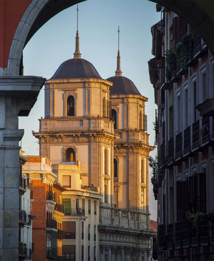 Church of San Isidro through one of the arches of the Plaza Mayor of Madrid