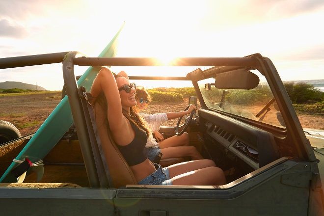 Ladies riding in open top jeep with surfboard