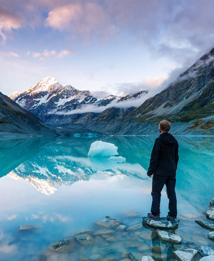 Hiker in front of lake looking at snow capped mountains