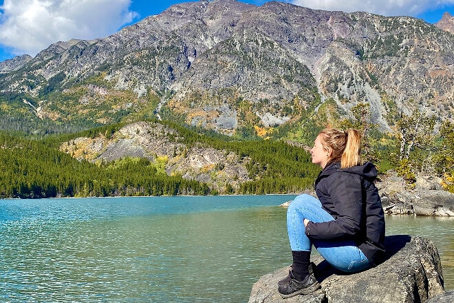 lady sitting on a mountain watching a glacier