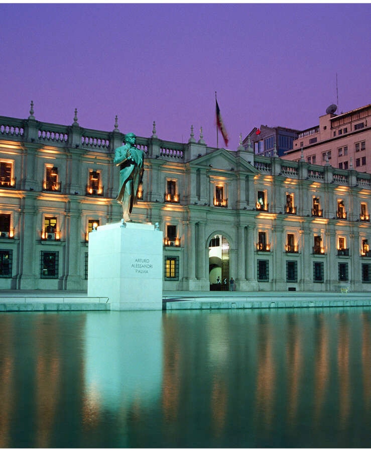 Palacio de la Moneda and statue of Arturo Alessandri Palma illuminated at dusk.