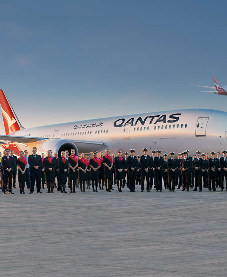 Staff in front of Dreamliner, with plane taking off in the background