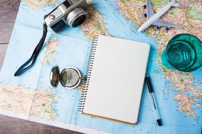 world map with camera, notepad and compass