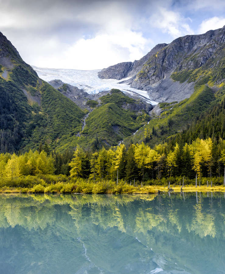 Glacial lake fringed by pine trees and snowy capped mountains