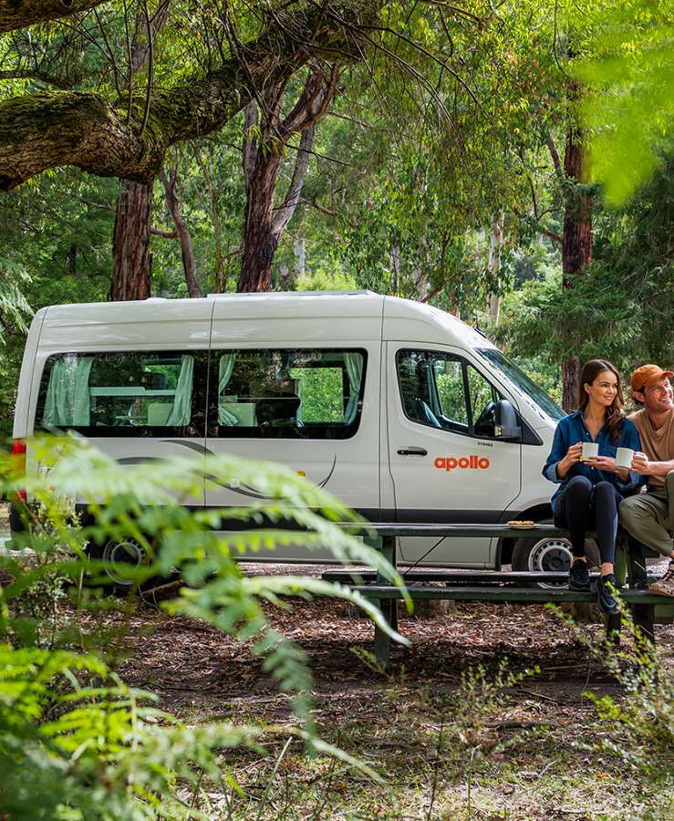 Couple enjoying a rest stop in natural bushland next to their Apollo motorhome