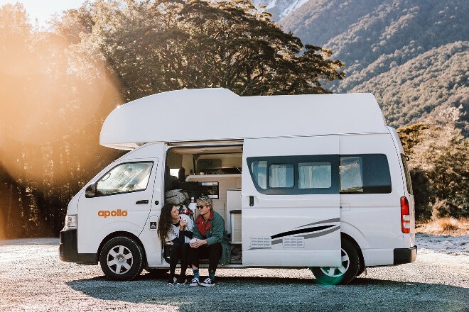 Couple enjoying refreshments in their Apollo camper at a rest stop