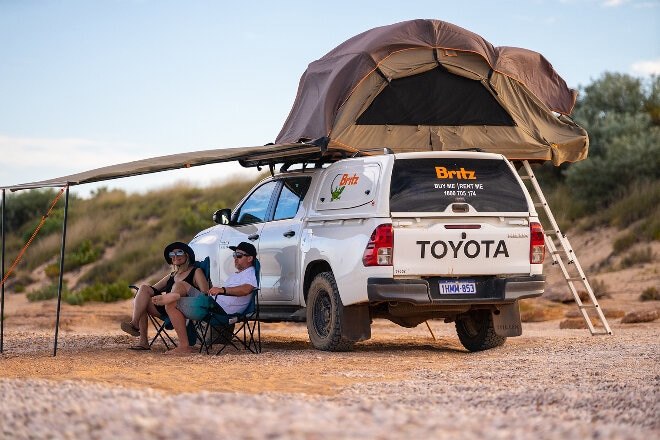 People sitting in the shade under a 4WD camper awning