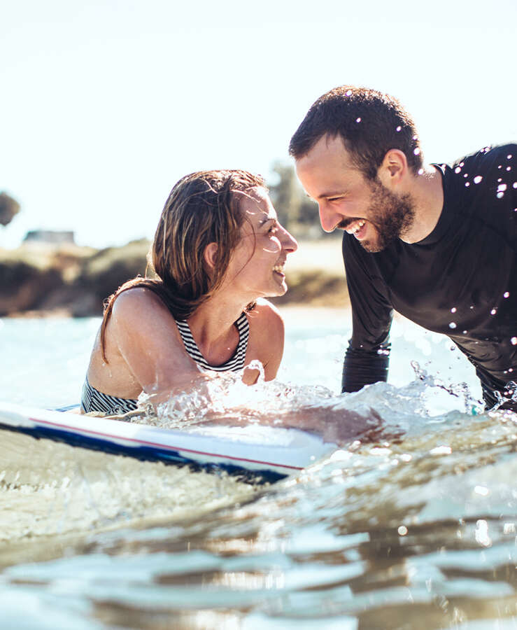 couple surfing in the ocean