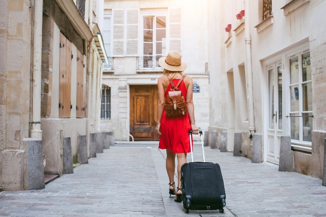 Woman walking down cobbled laneway with suitcase