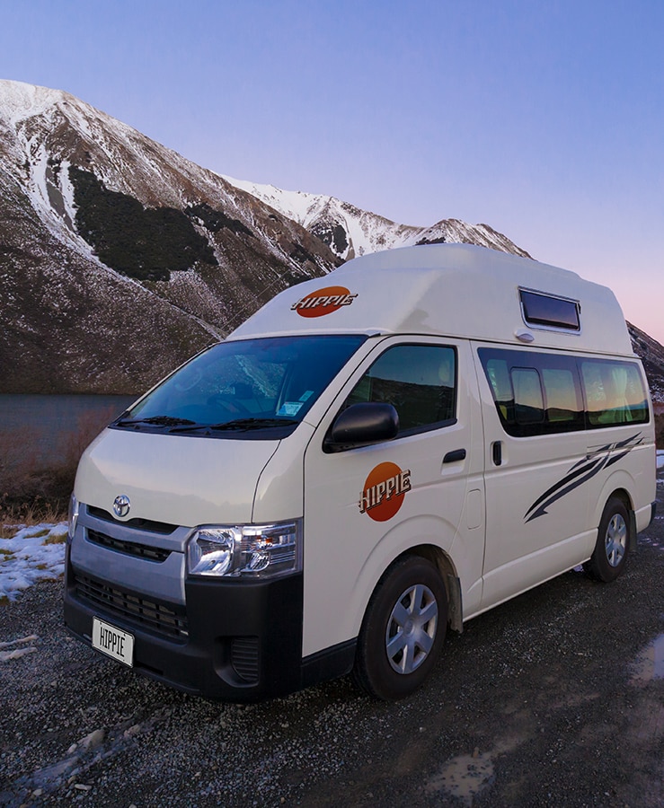 Hippie camper driving on a snowy alpine road