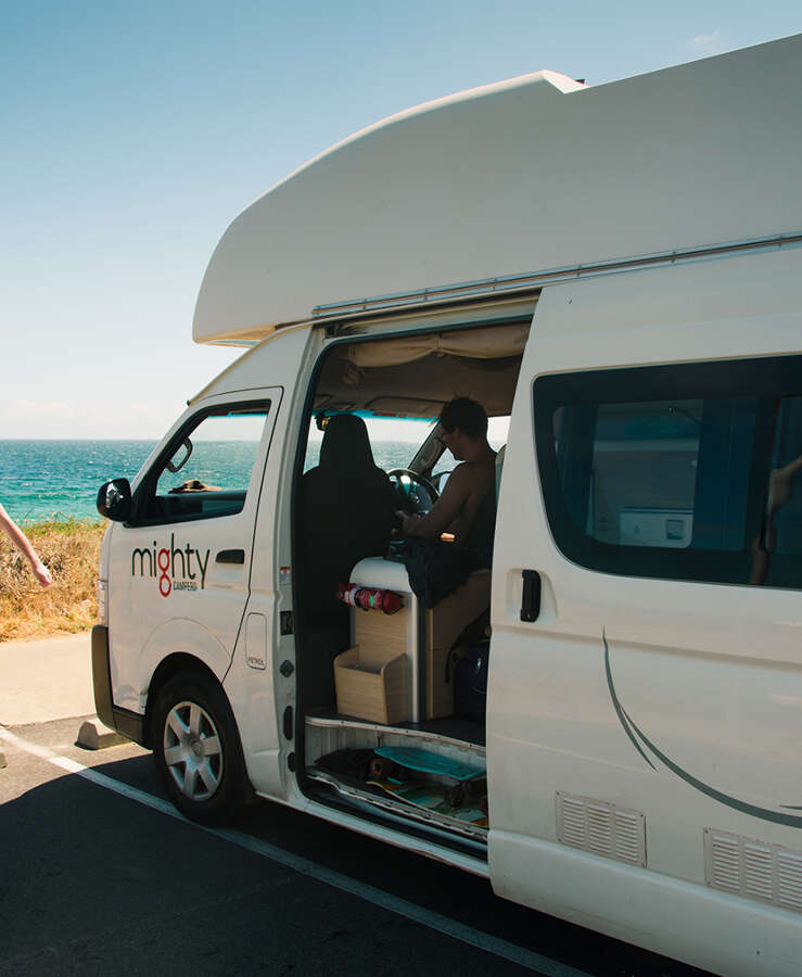 Mighty campervan parked next to a beach