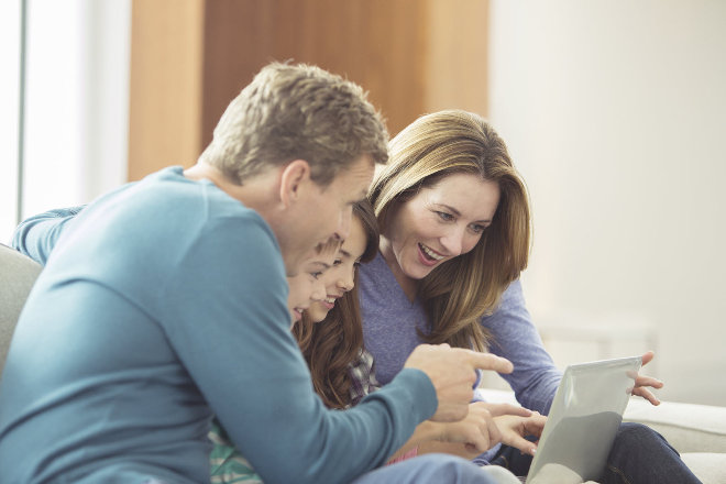 Smiling family using a laptop