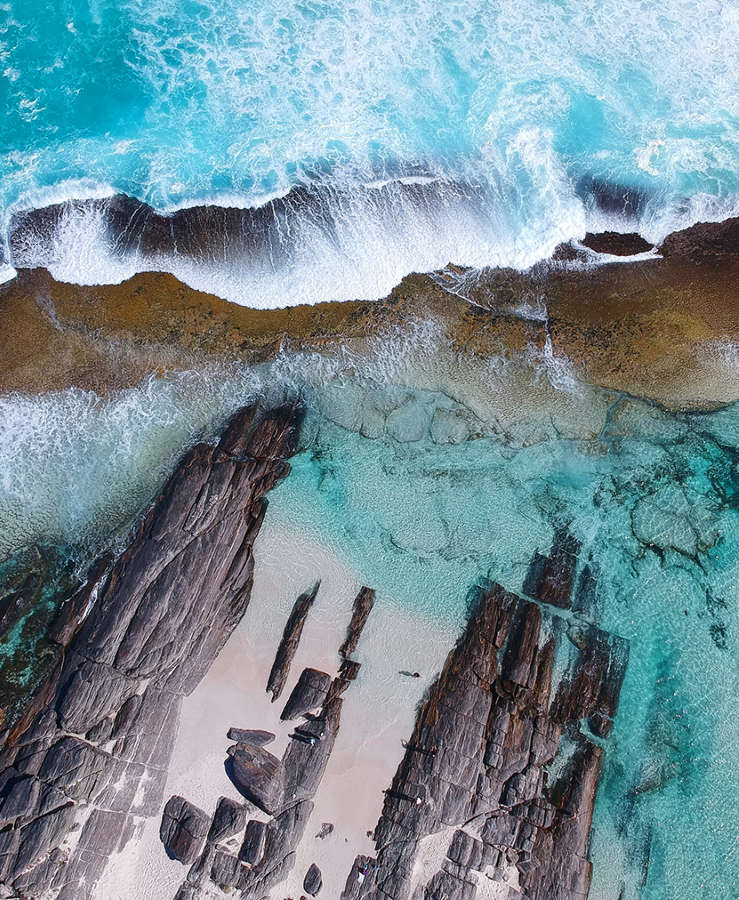 Aerial shot of ocean breaking on rocks