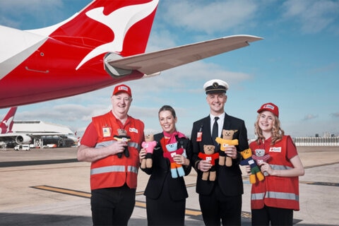 Qantas and Red cross staff on the tarmac with the aircraft in the background