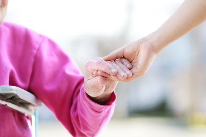 Elderly women holding hands with carer