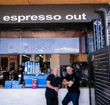 Dean Merlo and James Wilkinson from Merlo Coffee sitting bags of coffee beans