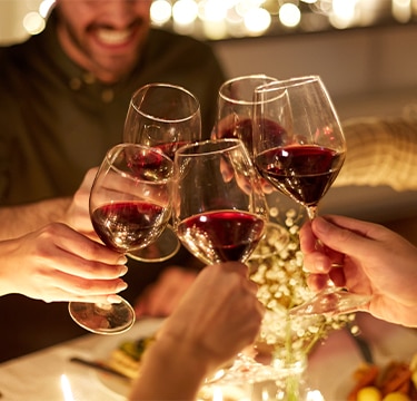 Group touching wine glasses at dinner table