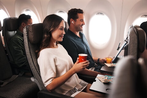 A couple comfortably seated in Economy on board an A220 plane