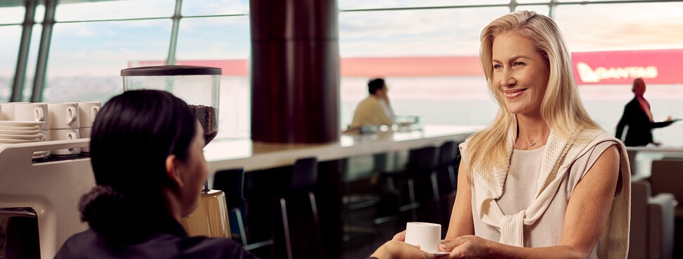 lady sitting in Qantas Club holding a glass of water